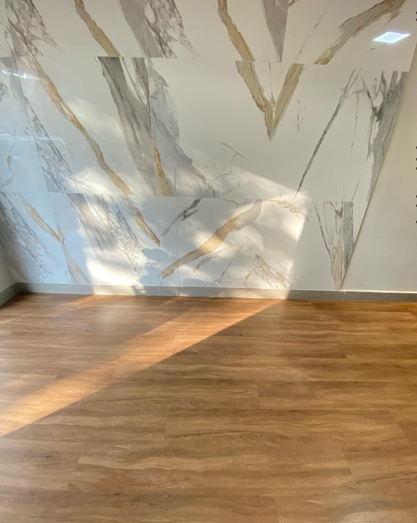 Acabamento perfeito de piso vinílico se conectando com parede marmorizada